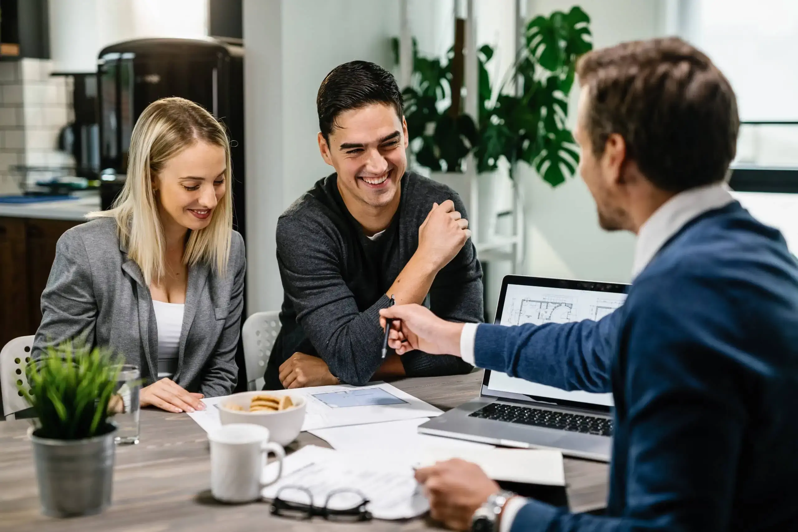 happy-couple-having-meeting-with-real-estate-agent-analyzing-blueprints-while-communicating-scaled