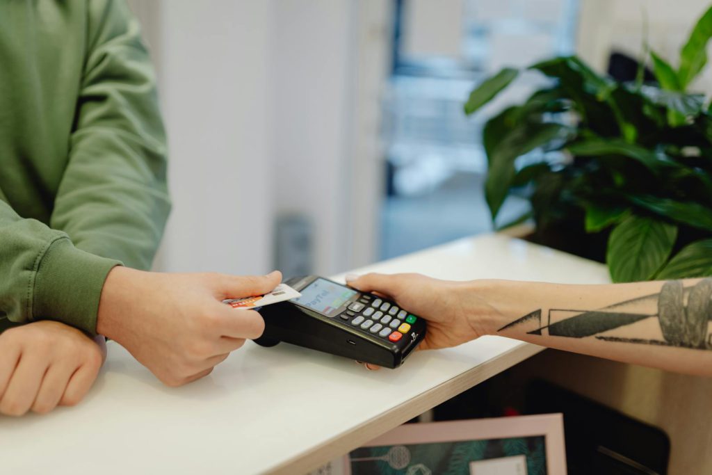 A close-up view of a contactless payment being made with a bank card over a payment terminal.